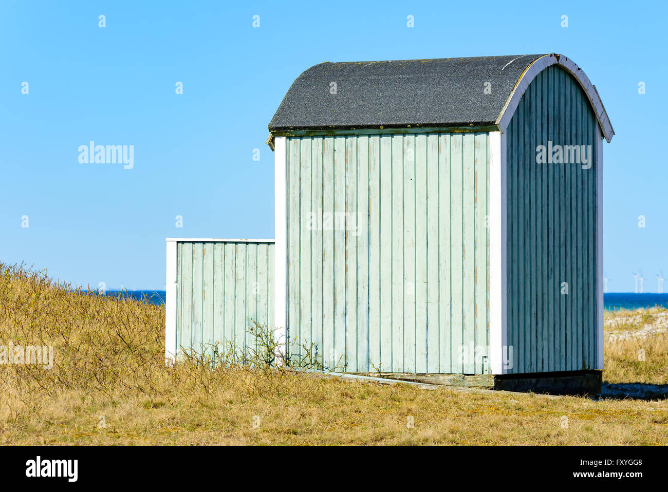 Falsterbo, Svezia - 11 Aprile 2016: Pastel Green in legno capanna sulla spiaggia o cabina balneare lungo il litorale sabbioso. Erba secca e san Foto Stock