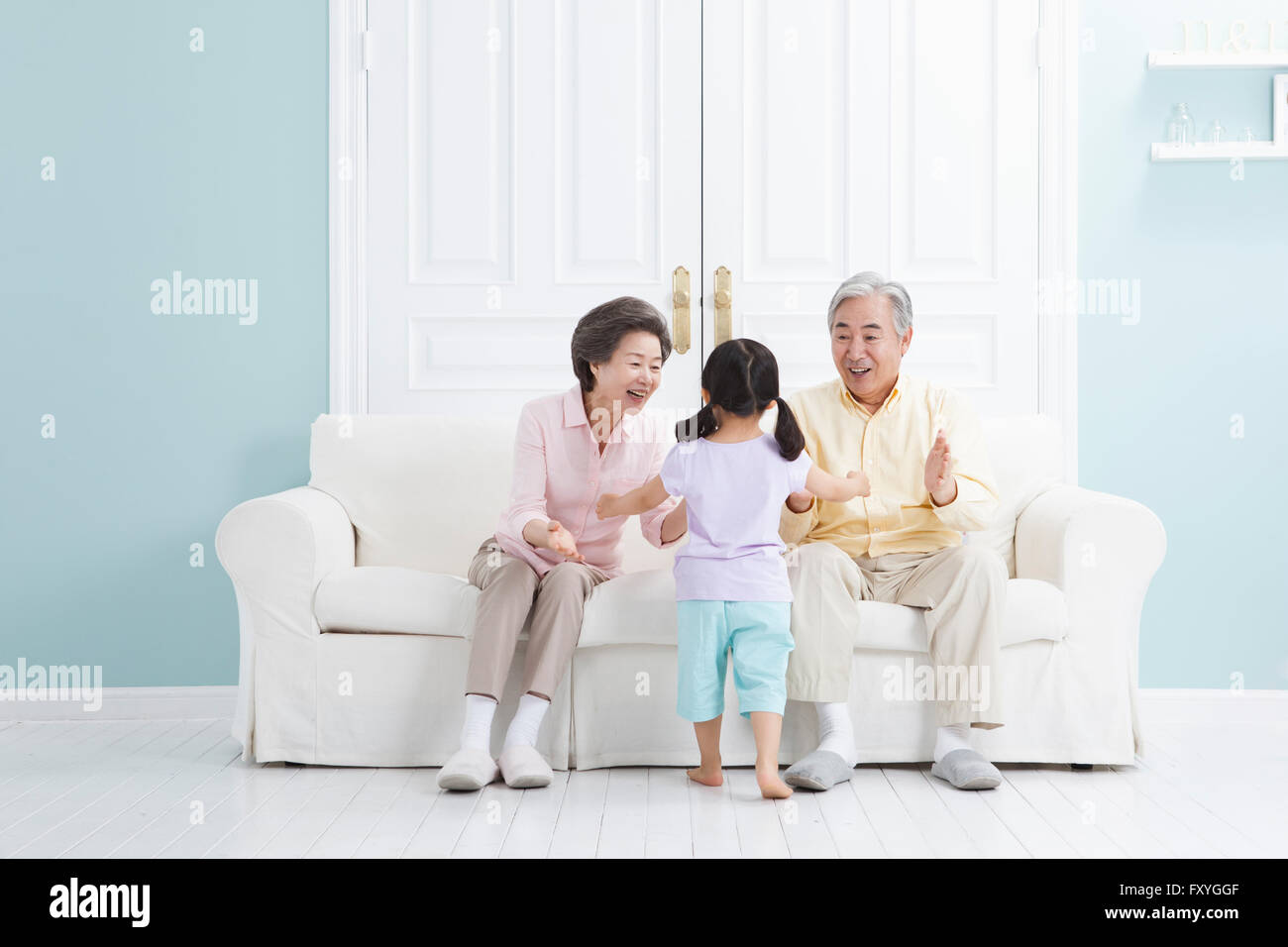 Coppia senior seduto su un divano sentirsi felice vedendo la loro nipote Foto Stock