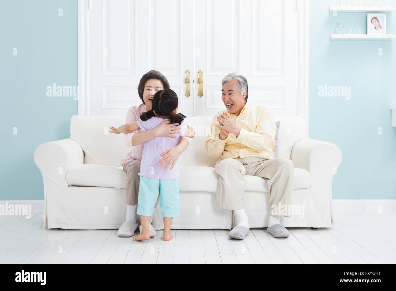 Coppia senior seduto su un divano e abbracciando il loro nipote con un sorriso Foto Stock