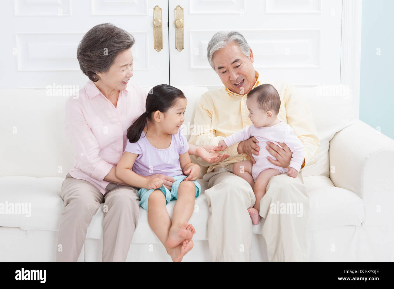 I nonni di essere felice con i loro nipoti tutti seduti su un lettino e sorridente Foto Stock