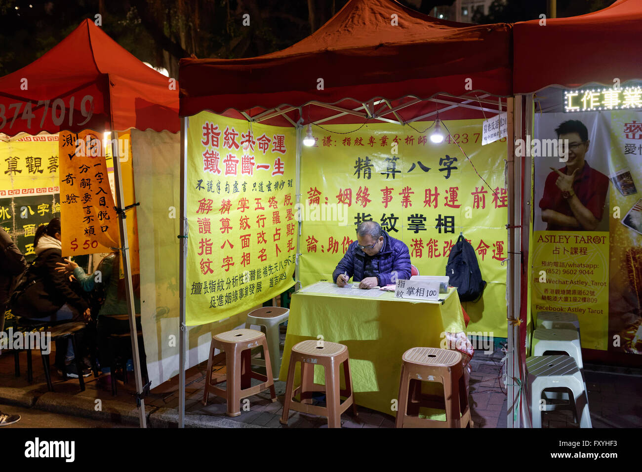 Il cinese indovini e lettori di Palm in una tenda illuminata, il Mercato Notturno di Temple Street, Yau Ma Tei, Kowloon, Hong Kong, Cina Foto Stock