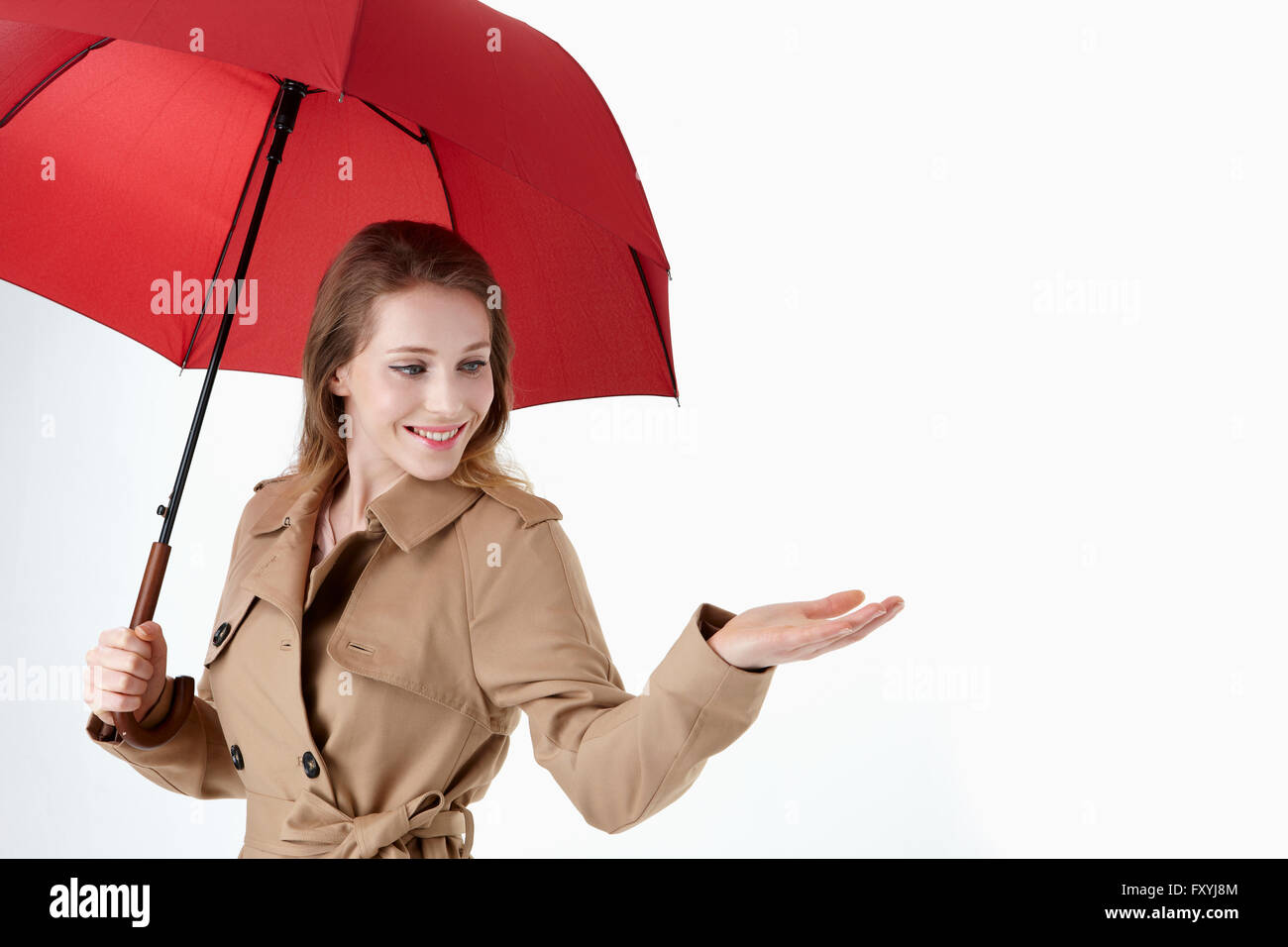 La donna a trench coat sotto ombrellone rosso Foto Stock
