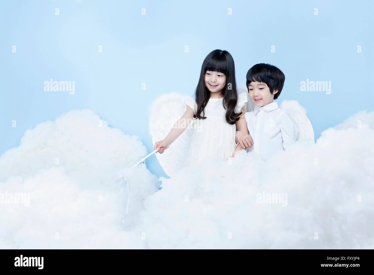 Un ragazzo e una ragazza in costume di angelo guardando giù in background che rappresenta il cielo Foto Stock