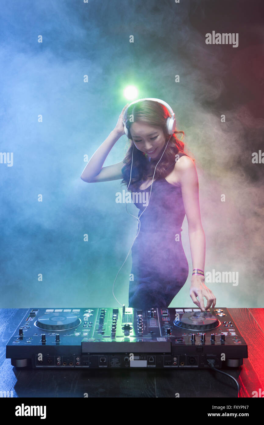 Giovane donna sorridente DJ guardando giù in discoteca Foto Stock