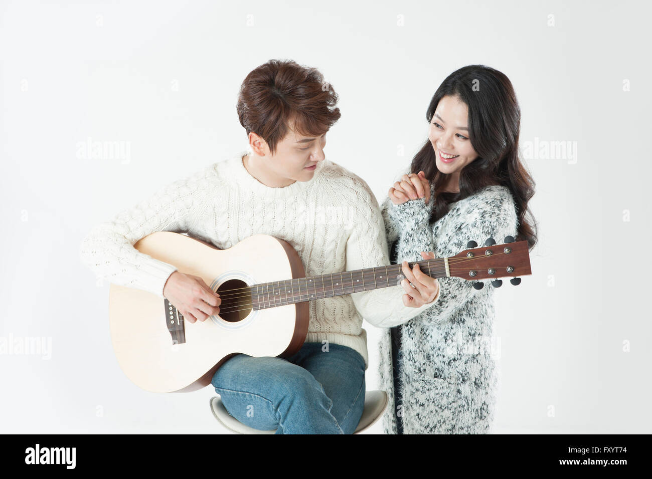 Giovane coppia sorridente di suonare una chitarra Foto Stock