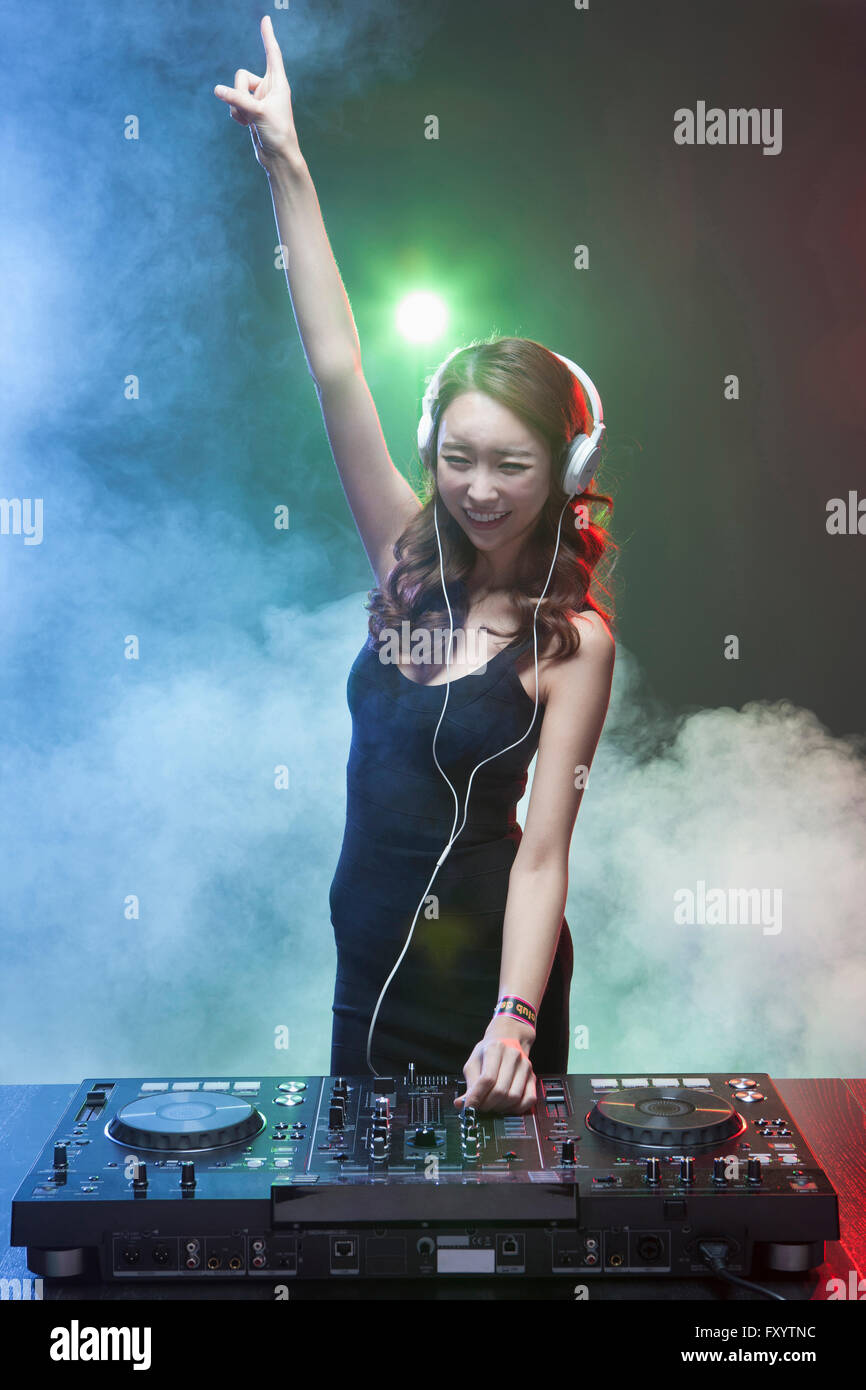 Giovane donna sorridente DJ riproduzione di musica tenendo la mano Foto Stock