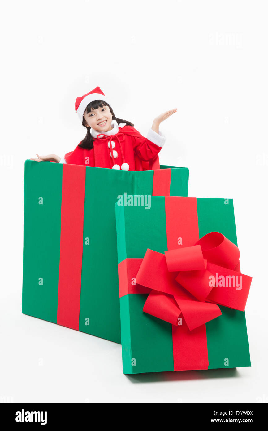 Ragazza sorridente in santa gli abiti tenendo la mano in una grande scatola presente aprendo le braccia fissando sulla parte anteriore Foto Stock