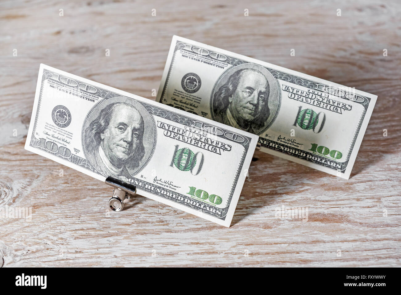 Il denaro nella clip di carta.banconote da cento dollari in clip di carta in piedi sul legno scuro dello sfondo. Denaro falso. Foto Stock