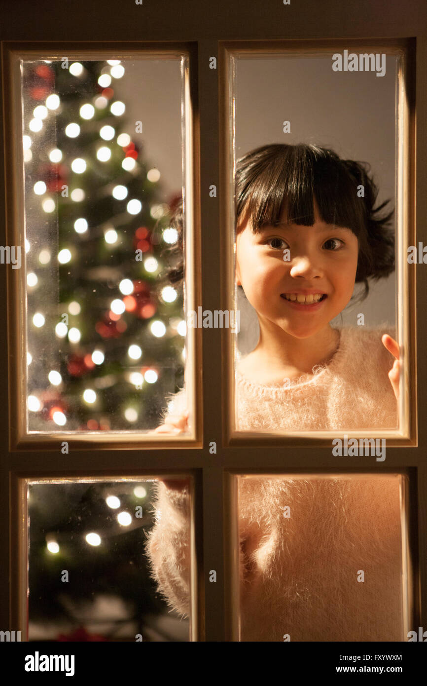 Ritratto di ragazza sorridente guardando fuori della finestra Foto Stock