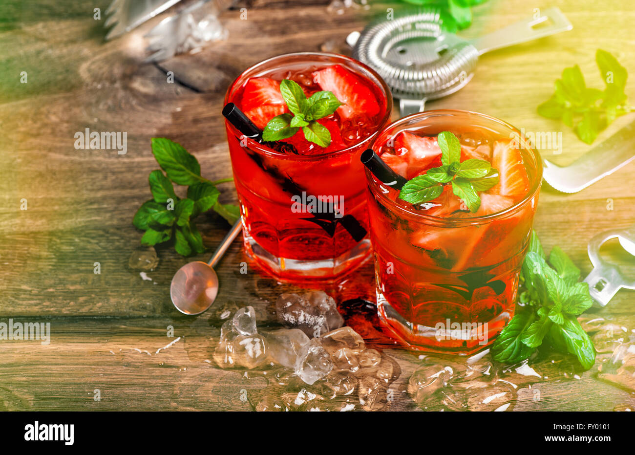 Red drink con Fragola, foglie di menta, ghiaccio. Cocktail bar con luci di partito Foto Stock