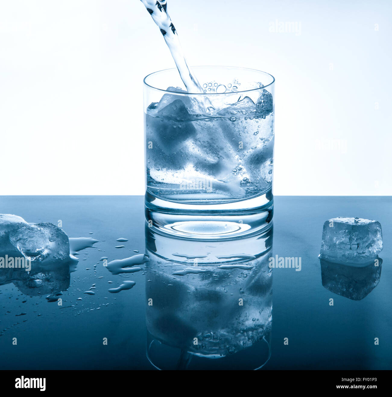 Acqua di bevanda fredda versando in vetro sopra lo sfondo luminoso. Blu immagine colorata Foto Stock