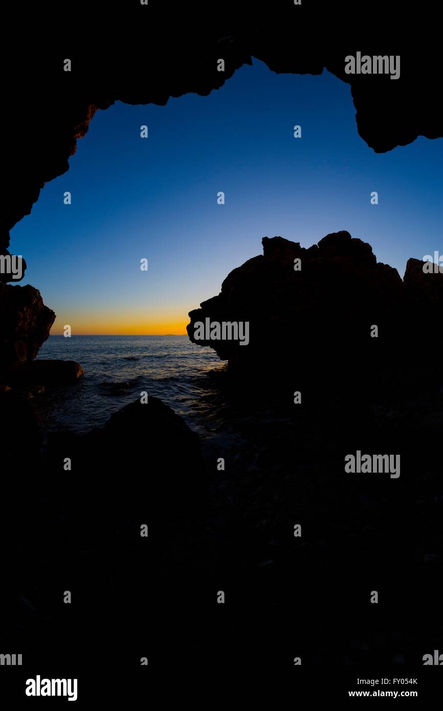 Entrata della caverna sulla costa del mare al tramonto tramonto orizzonte roccioso di pietra Foto Stock