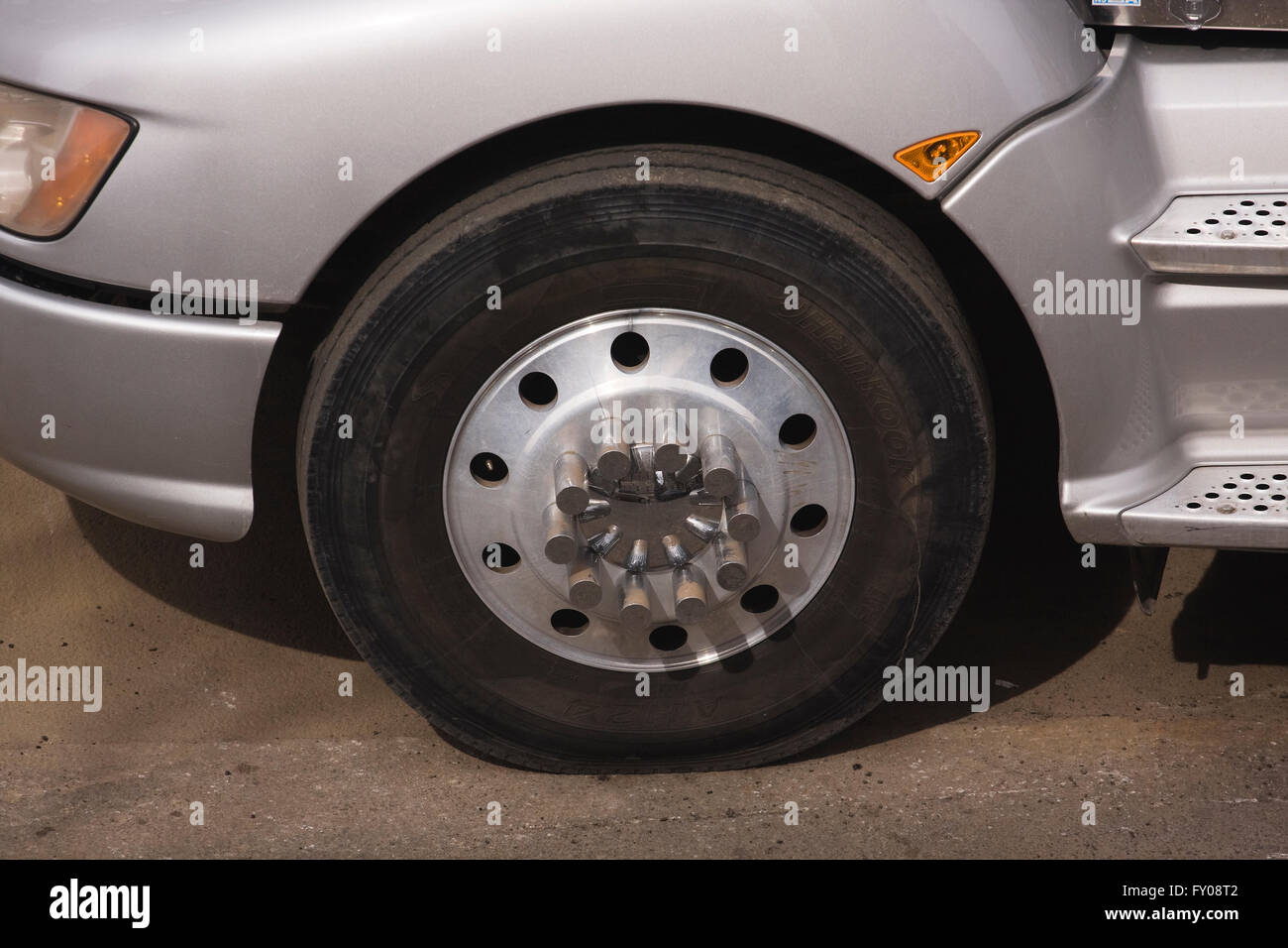 Ruota anteriore sinistra e ruota di un trattore rimorchio autoarticolato con incrinature del mozzo in alluminio e cromo il cappuccio del mozzo Foto Stock
