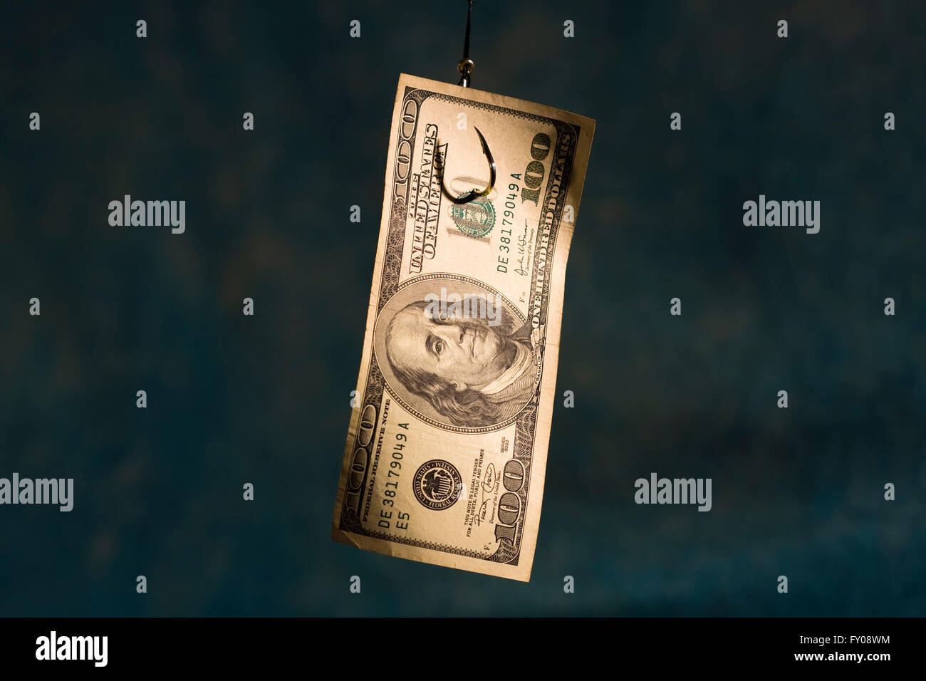 Un 100 dollaro appeso ad un gancio di pesca su sfondo azzurro. Foto Stock