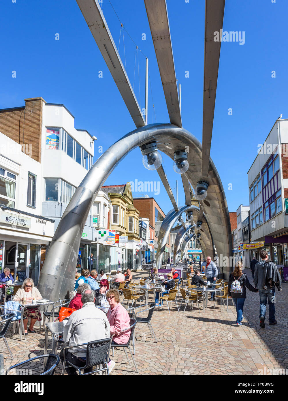 Sotto un cielo blu, turisti bere e mangiare al caffè in Church Street, Blackpool famoso per la molto moderna illuminazione stradale Foto Stock