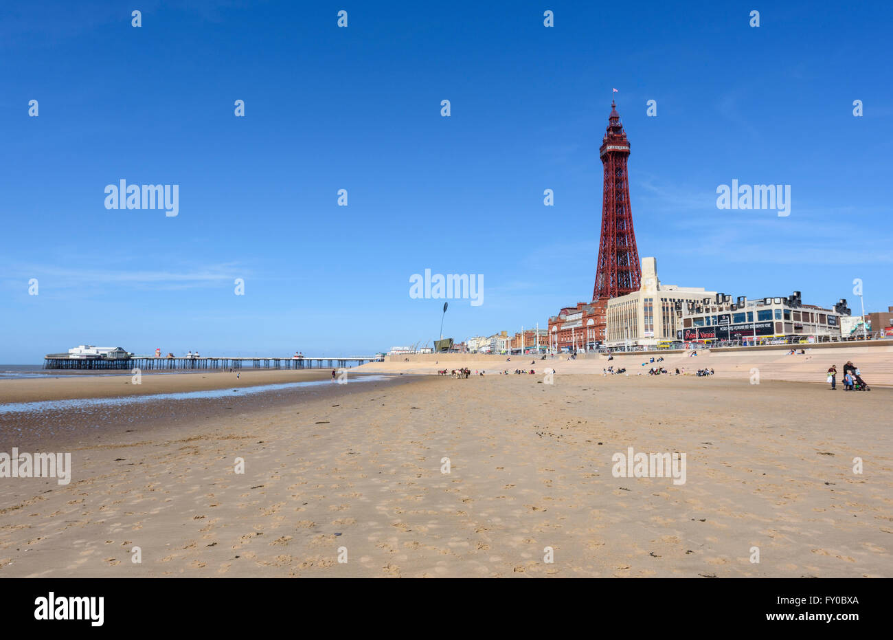 Sotto un luminoso cielo blu, la vista dalla spiaggia sabbiosa di North Pier e la mitica Torre di Blackpool in Blackpool Lancashire Foto Stock