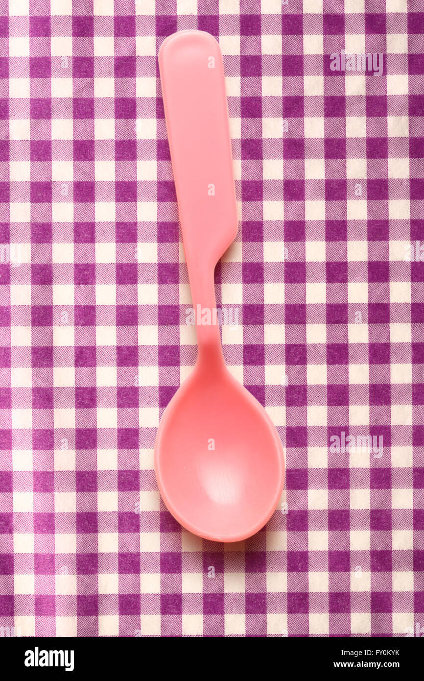 Rosa di stoviglie di plastica cucchiaio su sfondo lilla Foto Stock