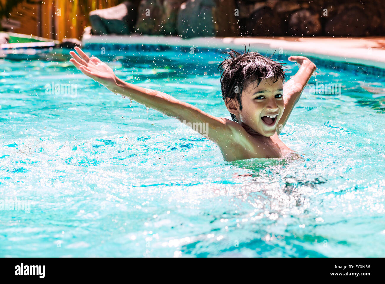 Ragazzo giovane ragazzo bambino otto anni spruzzi in piscina divertimento le attività per il tempo libero a braccia aperte Foto Stock