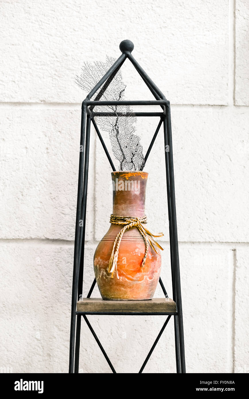 Pentola di creta coral home casa decor e disposizione degli elementi su di un supporto in metallo contro la parete Foto Stock