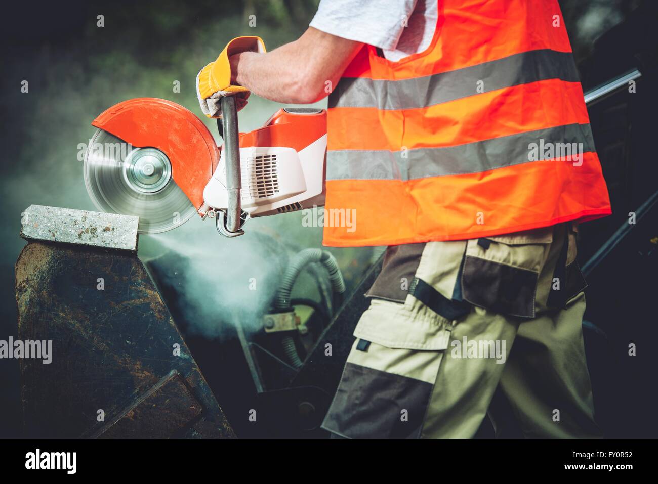 Taglio di calcestruzzo costruzione Power Tool Closeup Photo. Operaio edile il taglio del blocco in calcestruzzo mediante fresa elettrica. Foto Stock