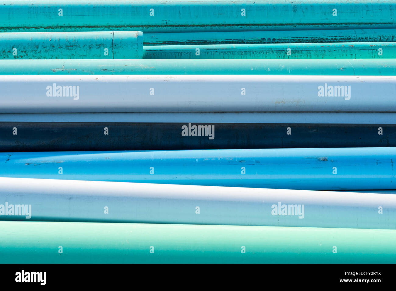 Abstract di blu, bianco e verde acqua tubi impilati in un cantiere in una giornata di sole Foto Stock