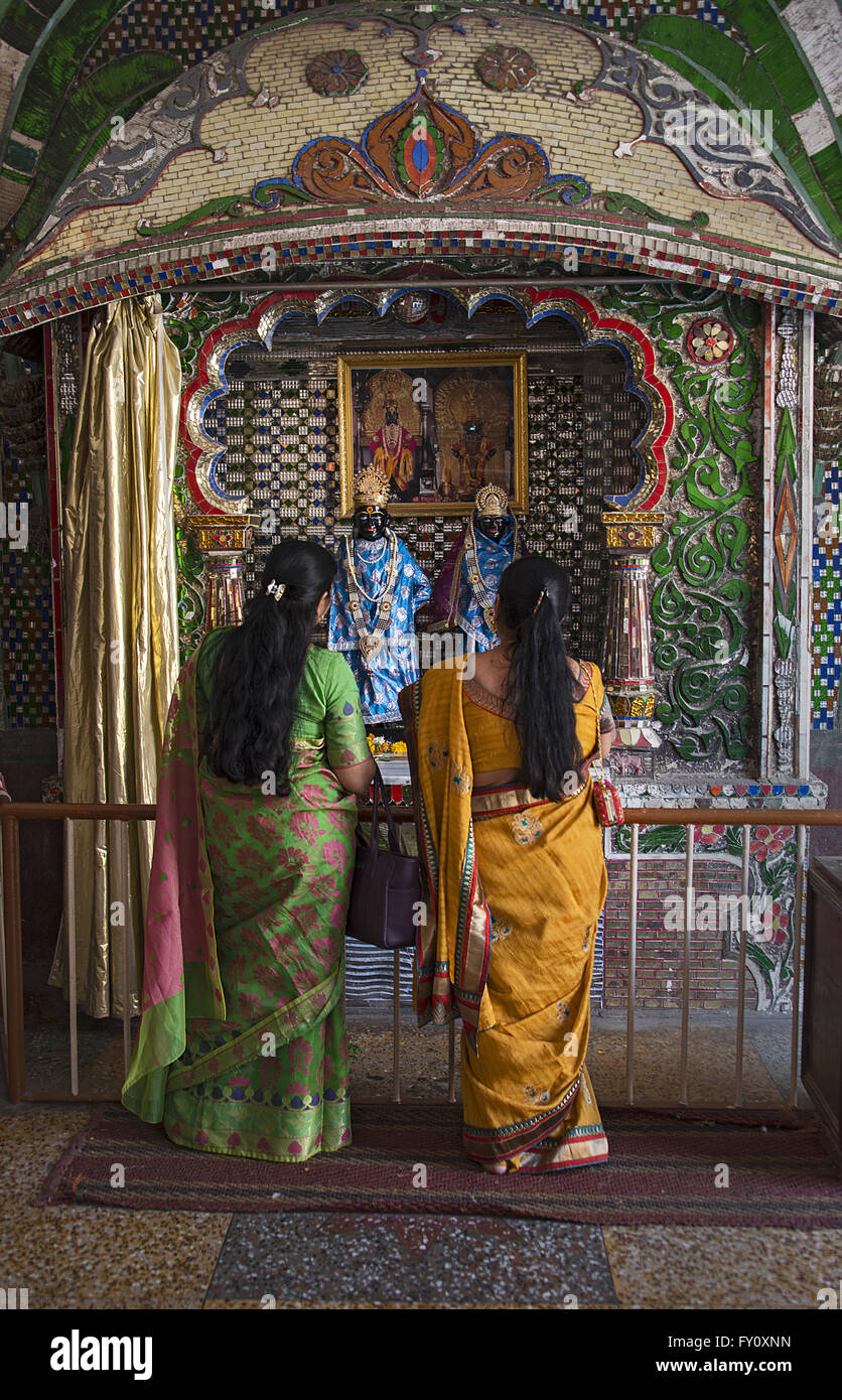 Due donne vestite nel tradizionale sari pregare la divinità di Krishna e la sua consorte Radha presso il tempio di Krishna in Mumbai Foto Stock