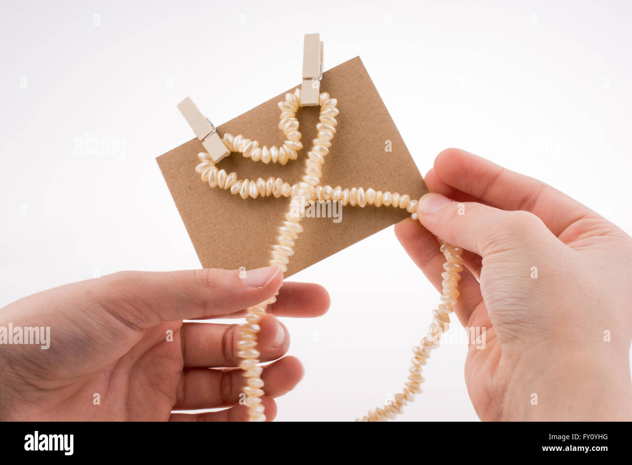 Collana di perle costituisce forma di cuore su carta su sfondo bianco Foto Stock