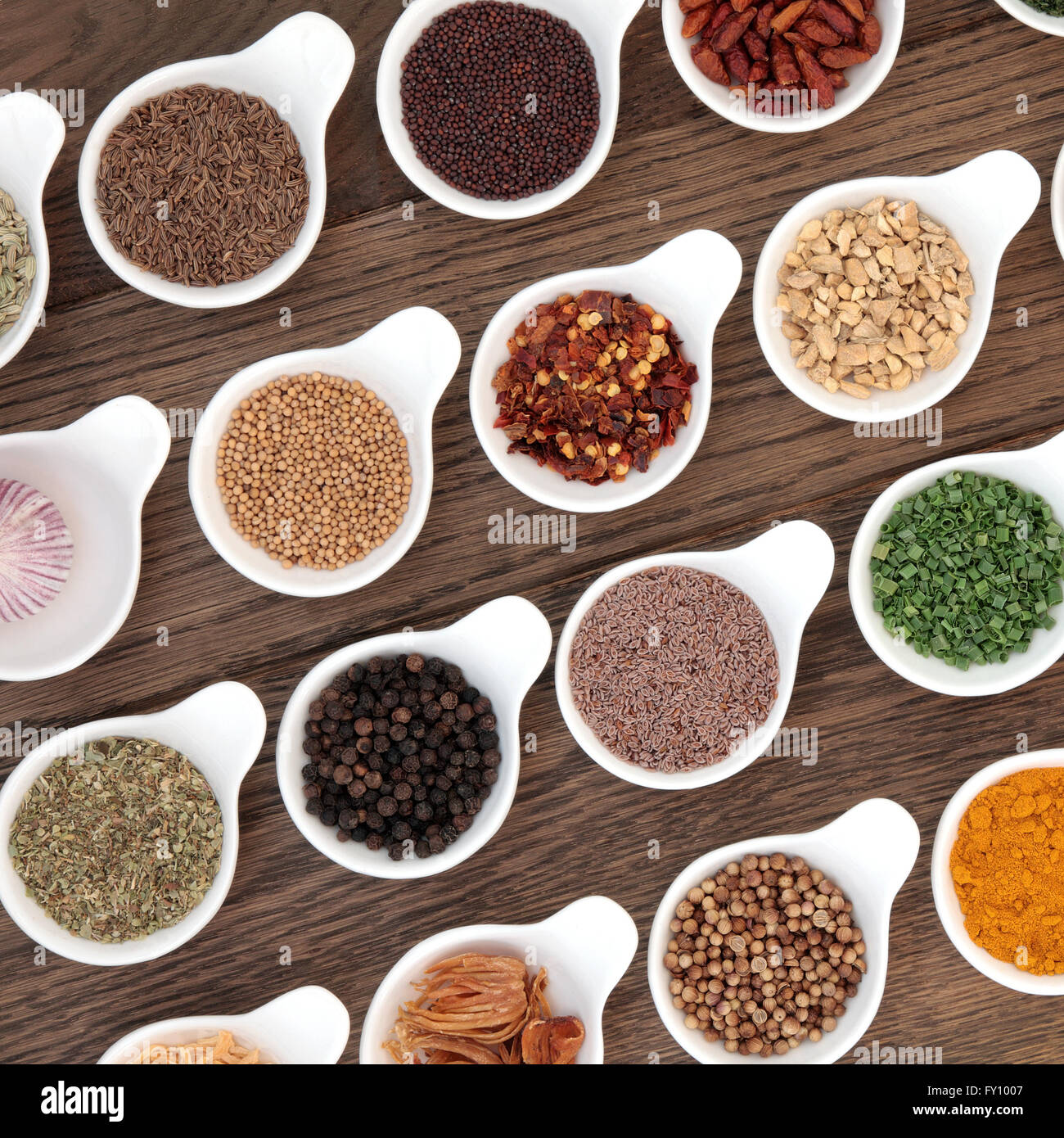 Spezie ed erbe in selezione ciotole di porcellana sulla vecchia quercia sullo sfondo. Foto Stock