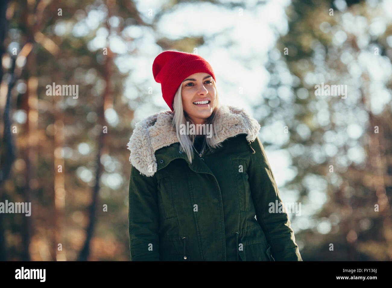 Basso angolo vista di felice giovane donna indossa knit hat e giacca mentre guarda lontano Foto Stock