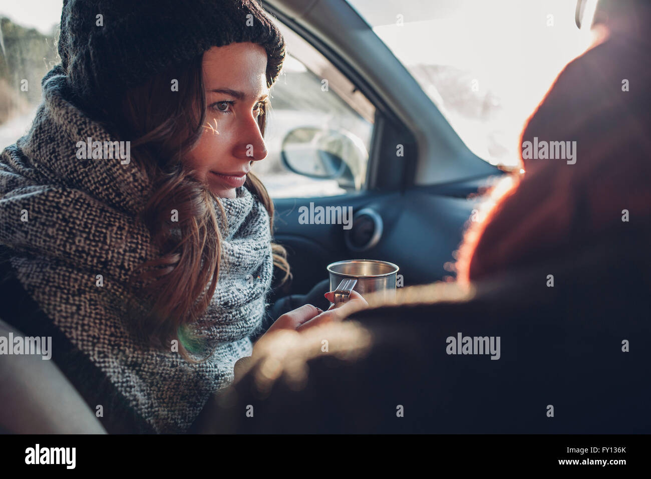 Giovane donna azienda tazza da caffè guardando un uomo in auto Foto Stock