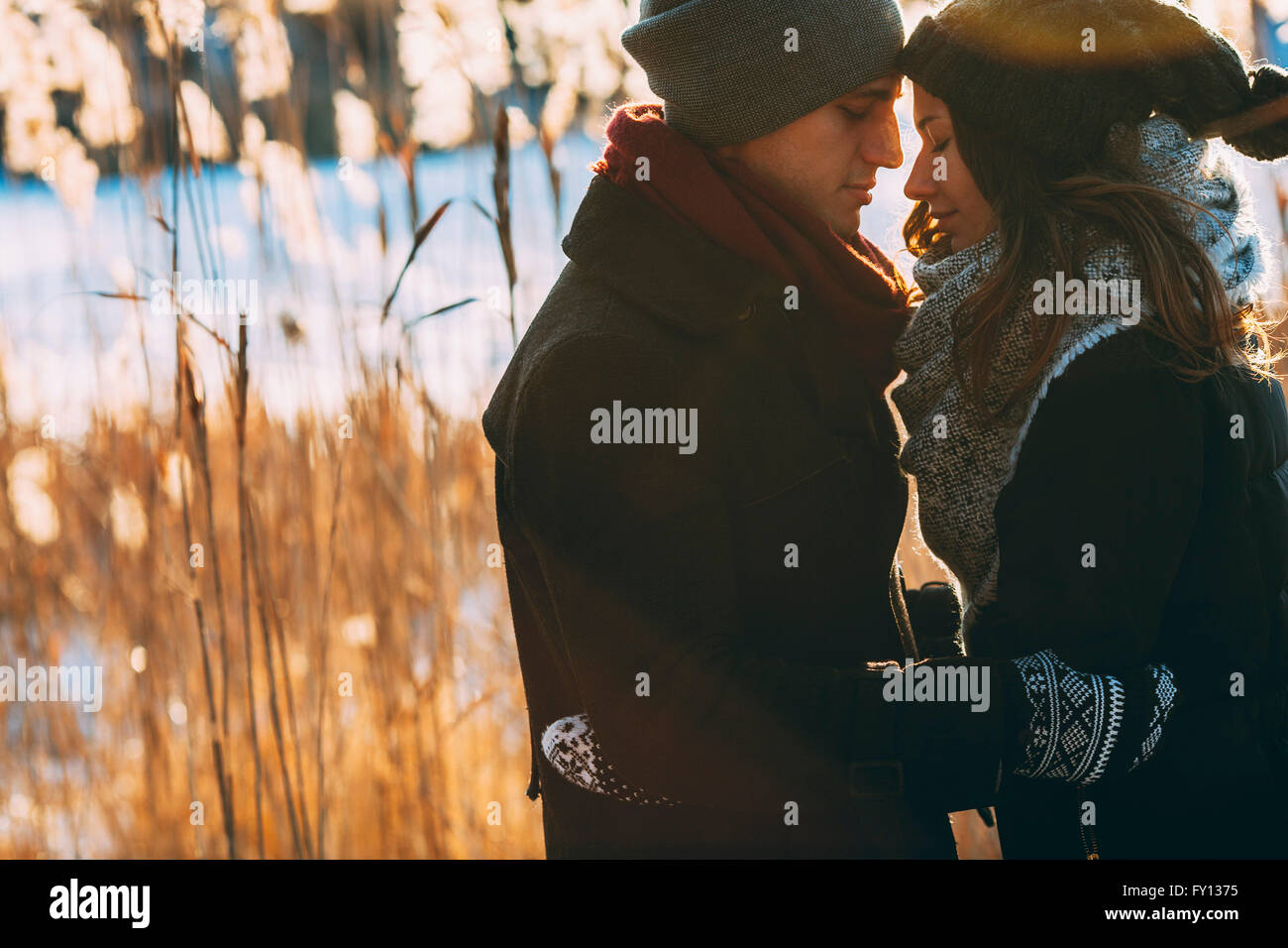 Coppia giovane abbracciando mentre si sta in piedi sul campo durante il periodo invernale Foto Stock
