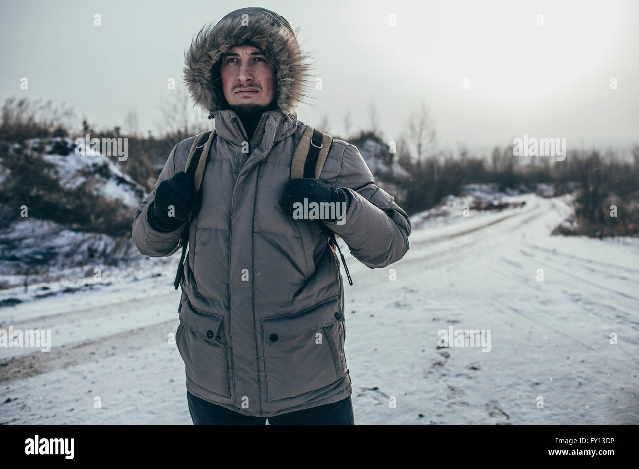 Riflessivo escursionista che porta uno zaino mentre in piedi su paesaggi innevati Foto Stock
