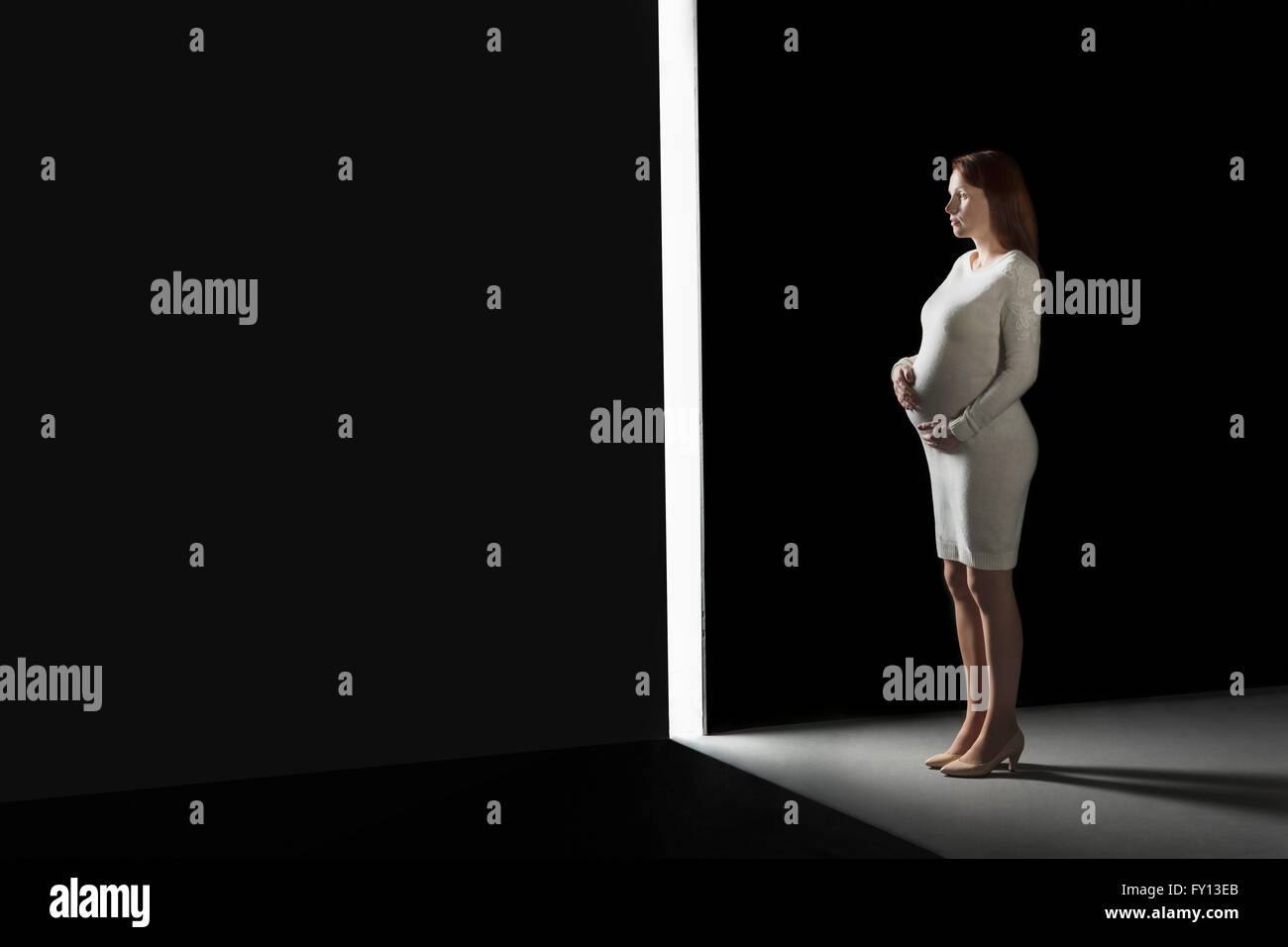 Lunghezza completa donna incinta guardando attraverso l'apertura nella parete Foto Stock