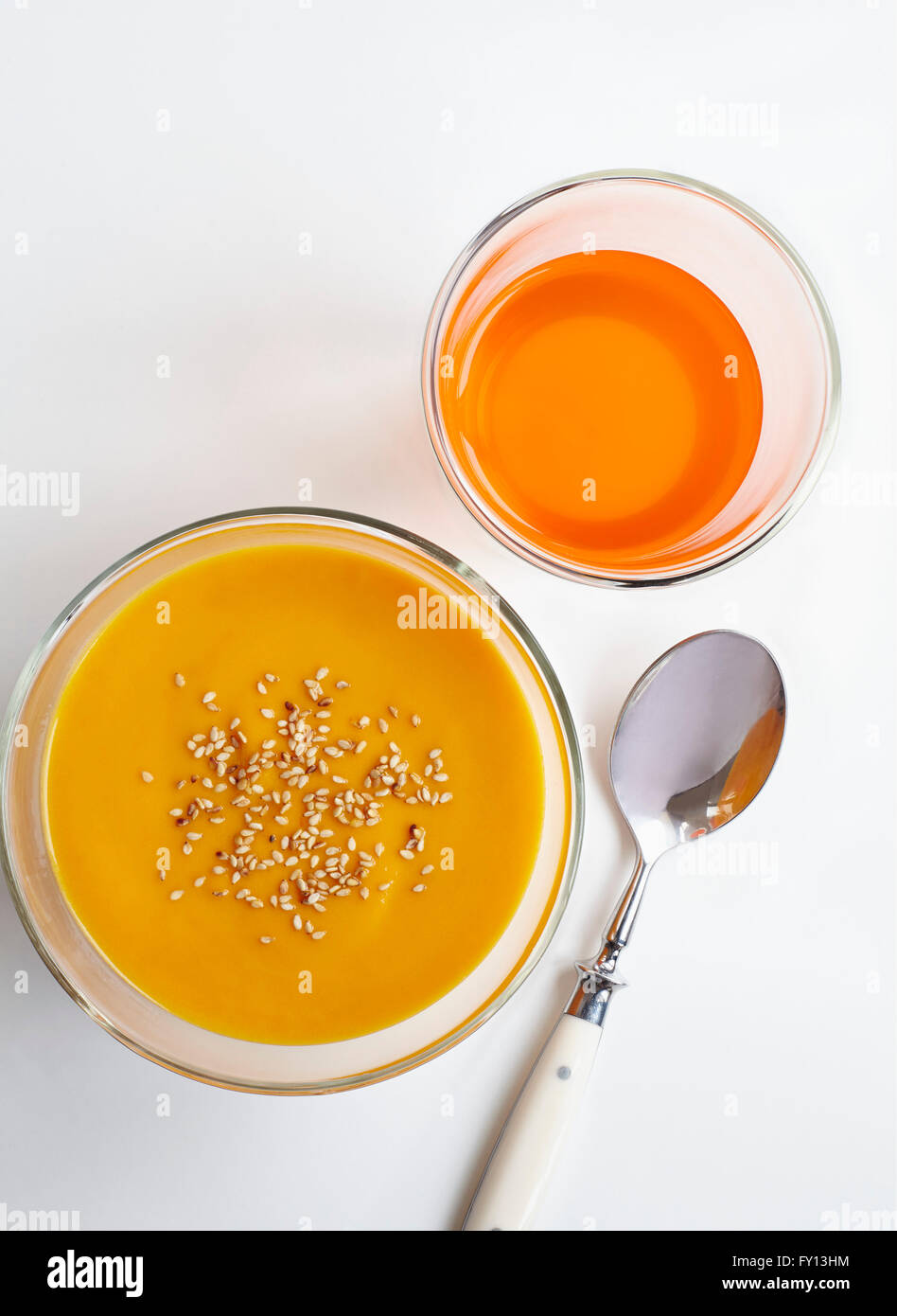 Angolo di alta vista di purea di carota e drink con cucchiaio su sfondo bianco Foto Stock