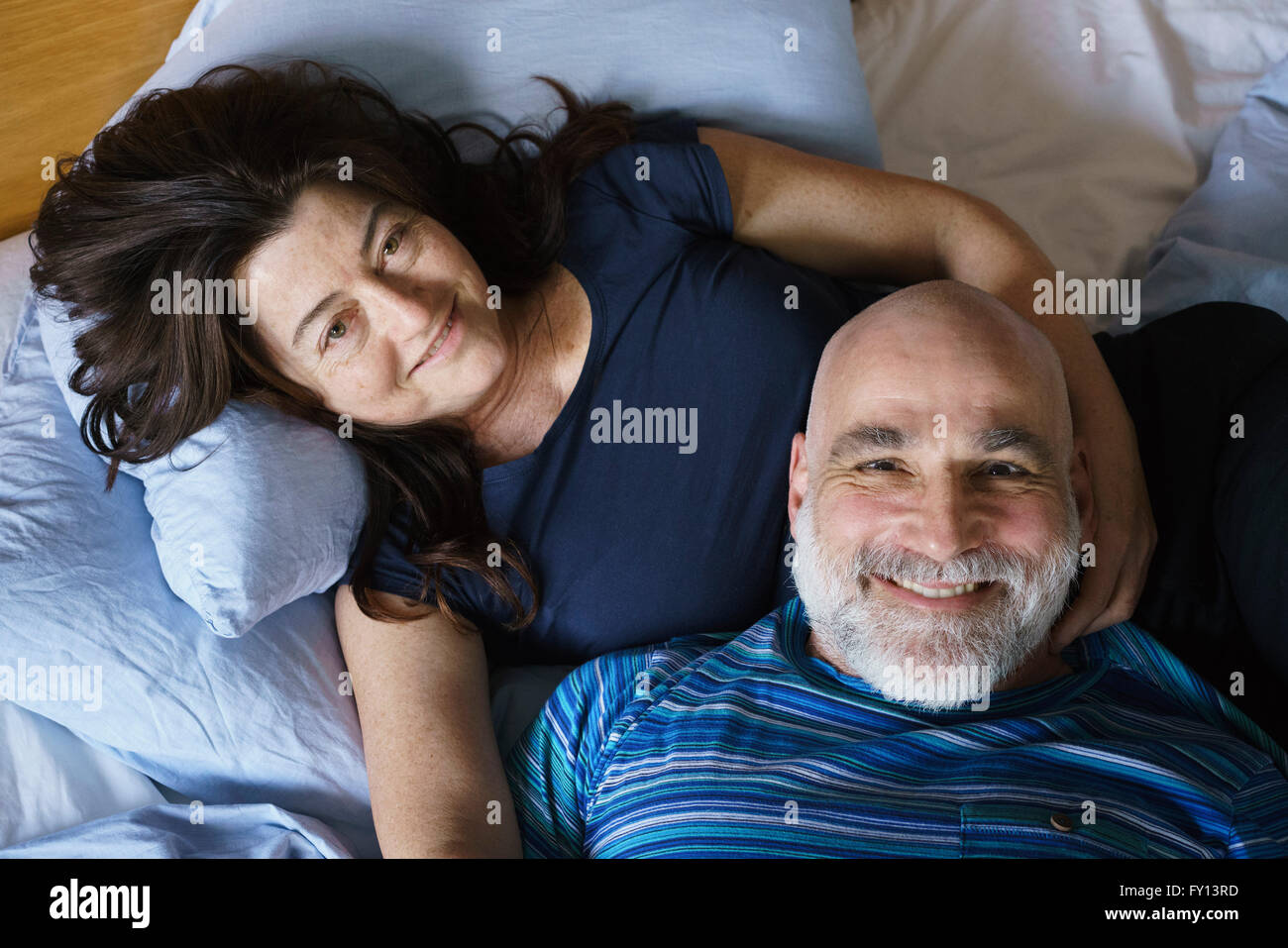 Angolo di Alta Vista della coppia matura giacente sul letto di casa Foto Stock