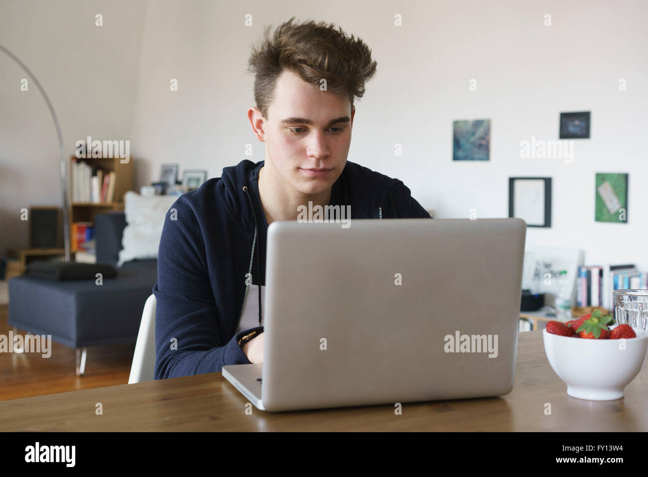 Ragazzo adolescente utilizzando computer portatile sul tavolo a casa Foto Stock