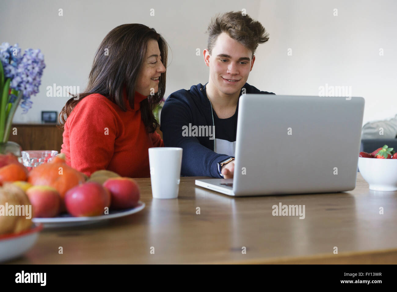 Sorridente madre e figlio utilizzando computer portatile sul tavolo a casa Foto Stock
