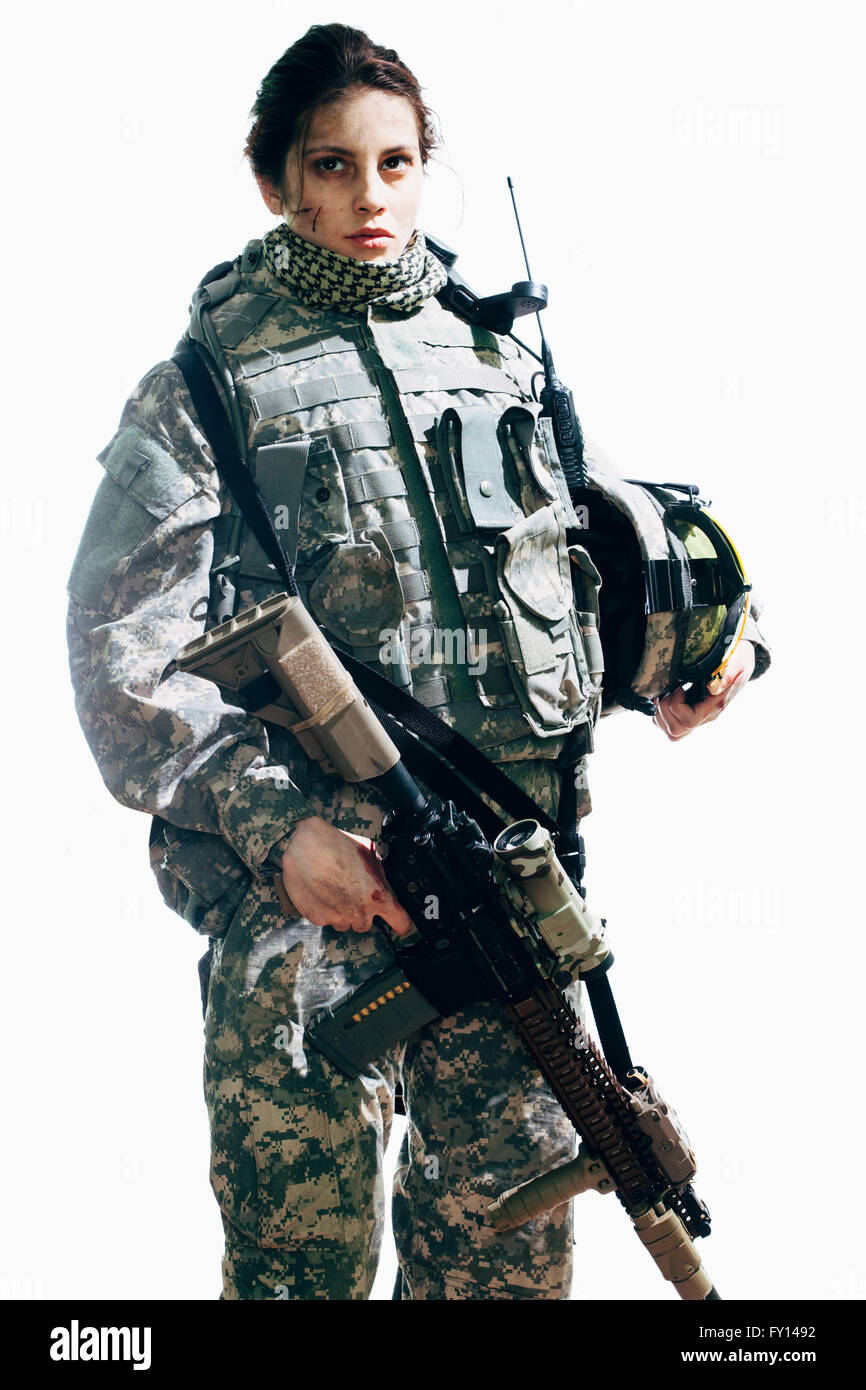 Soldato femmina holding fucile e casco mentre in piedi contro uno sfondo bianco Foto Stock