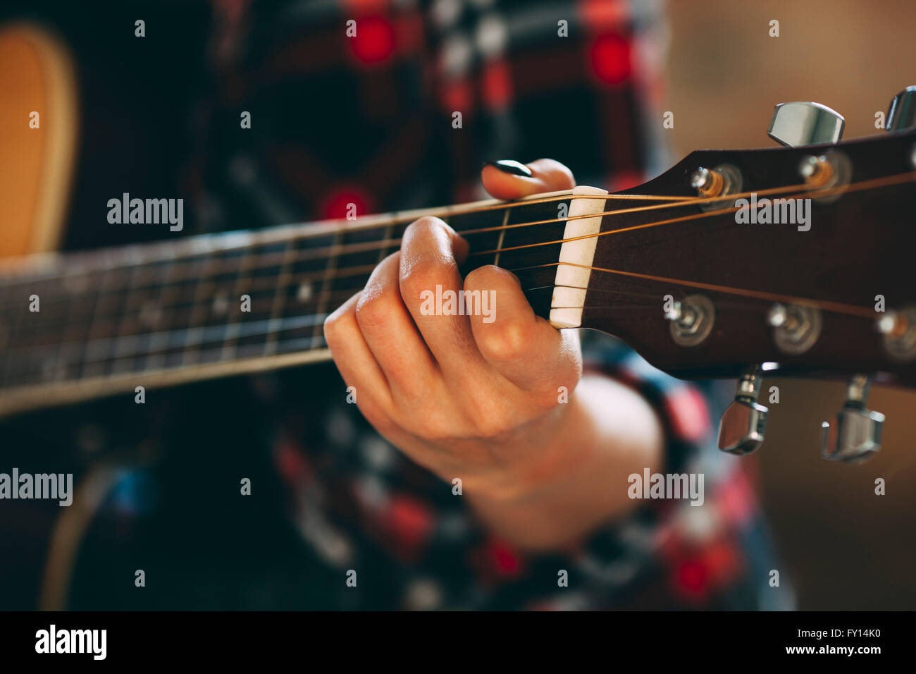 Immagine ritagliata della giovane donna a suonare la chitarra a casa Foto Stock