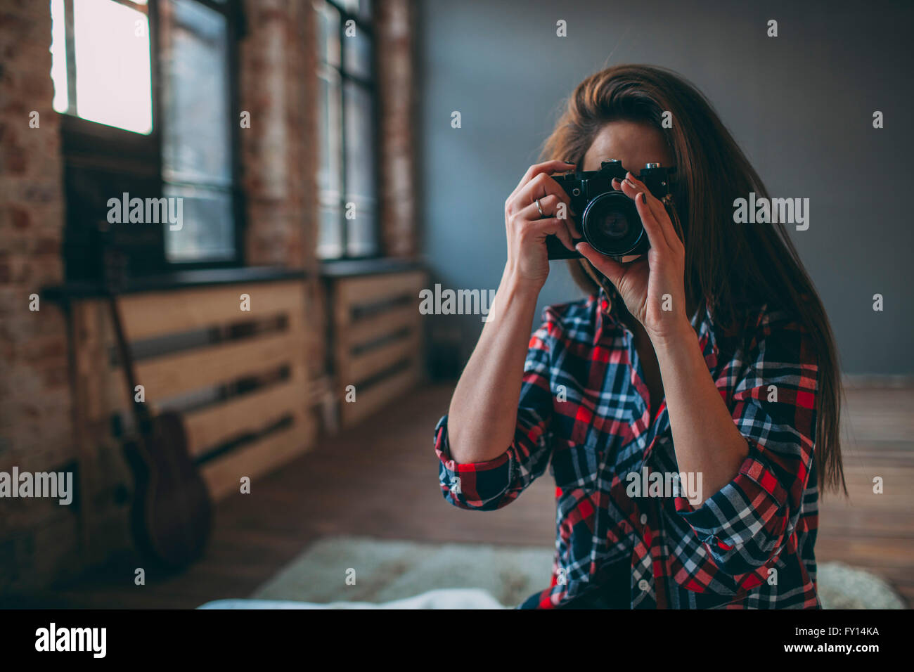 Donna fotografare attraverso la fotocamera reflex in camera da letto a casa Foto Stock