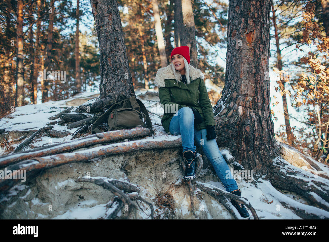 Per tutta la lunghezza della giovane donna seduta nella coperta di neve forest Foto Stock