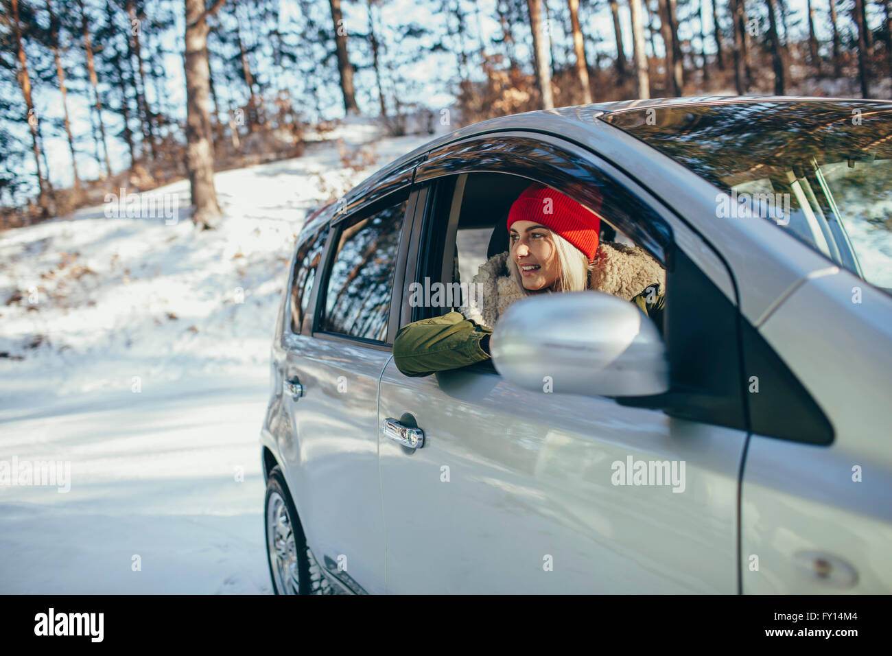 Felice giovane donna in auto durante il periodo invernale Foto Stock