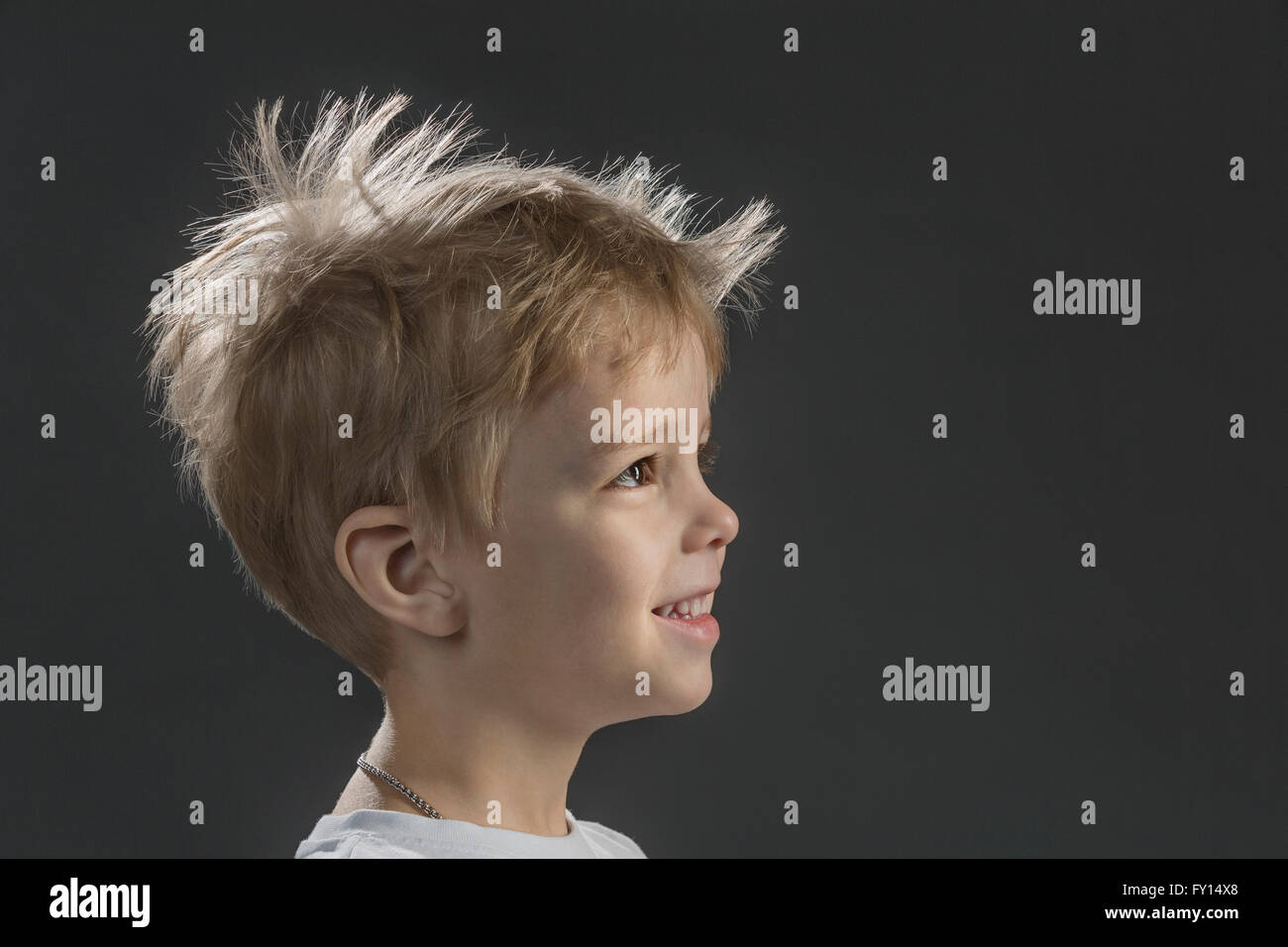Close-up vista laterale di felice ragazzo contro uno sfondo grigio Foto Stock