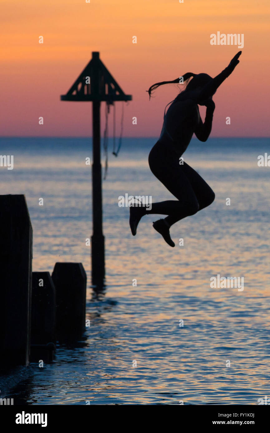 Aberystwyth, Wales, Regno Unito. Il 20 aprile 2016. Alla fine di un glorioso giorno di primavera, un gruppo di giovani continuano tyo godervi il giorno al tramonto le immersioni da un pontile in legno in mare. Credito: Alan Hale/Alamy Live News Foto Stock