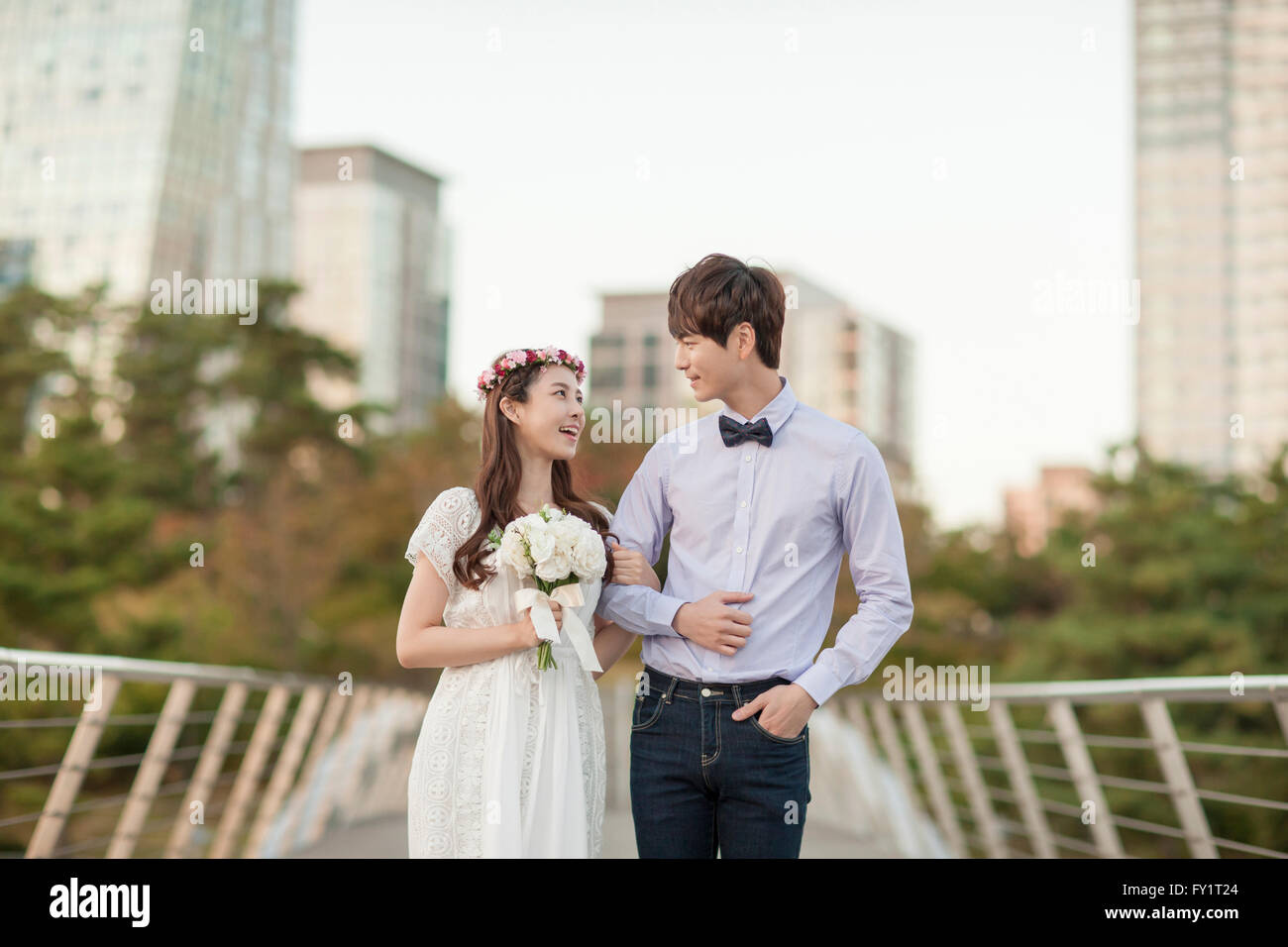 Giovani sorridenti sposi a braccetto faccia a faccia al parco Foto Stock