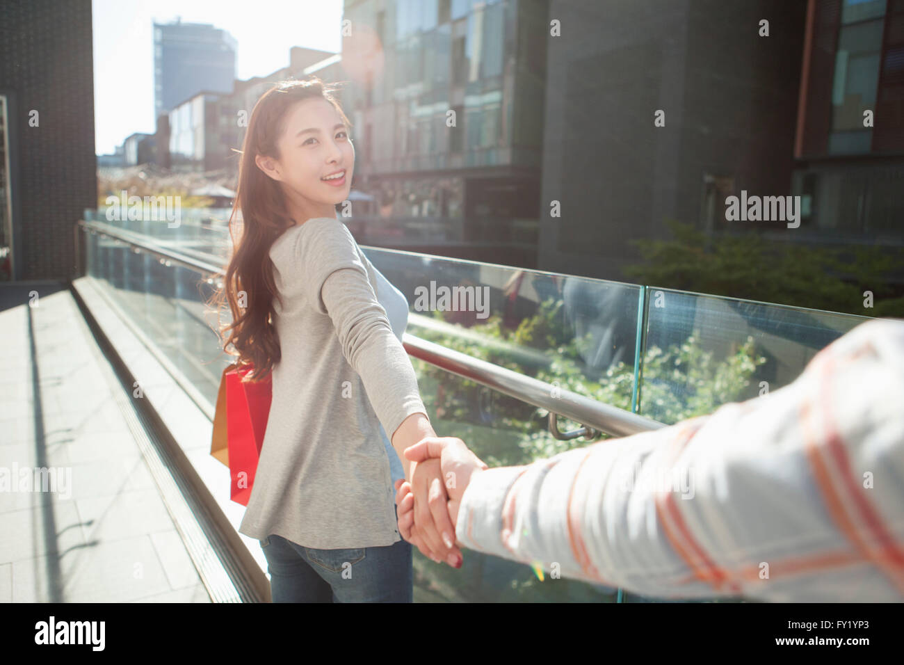 Donna con le borse della spesa tirando fuori il suo fidanzato la mano al di fuori Foto Stock