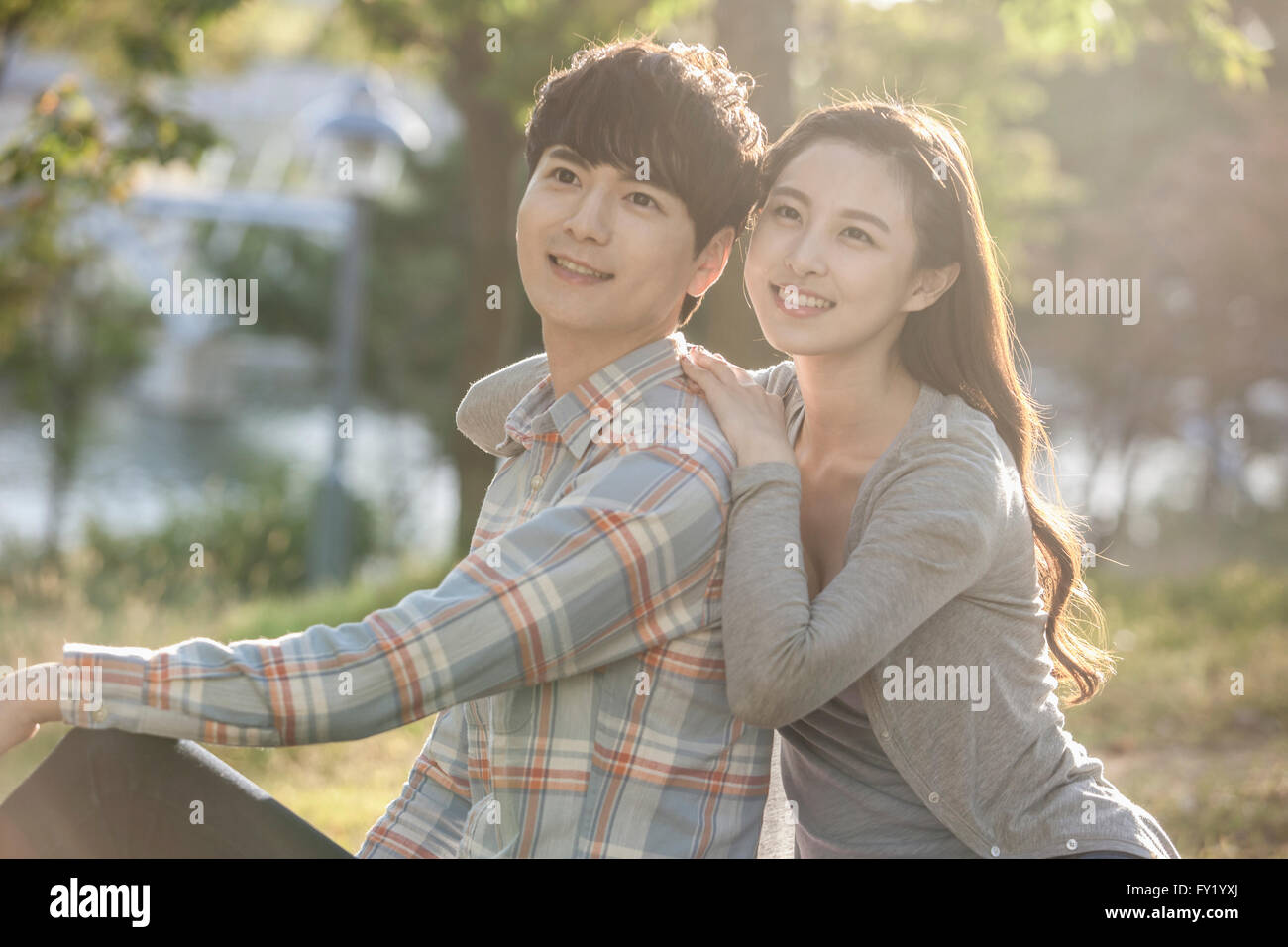 Donna appoggiata al suo ragazzo della spalla e sia con lo sguardo in alto con un sorriso a park Foto Stock