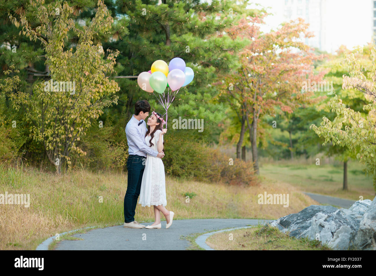 Sposa e lo sposo permanente al parco con palloncini Foto Stock