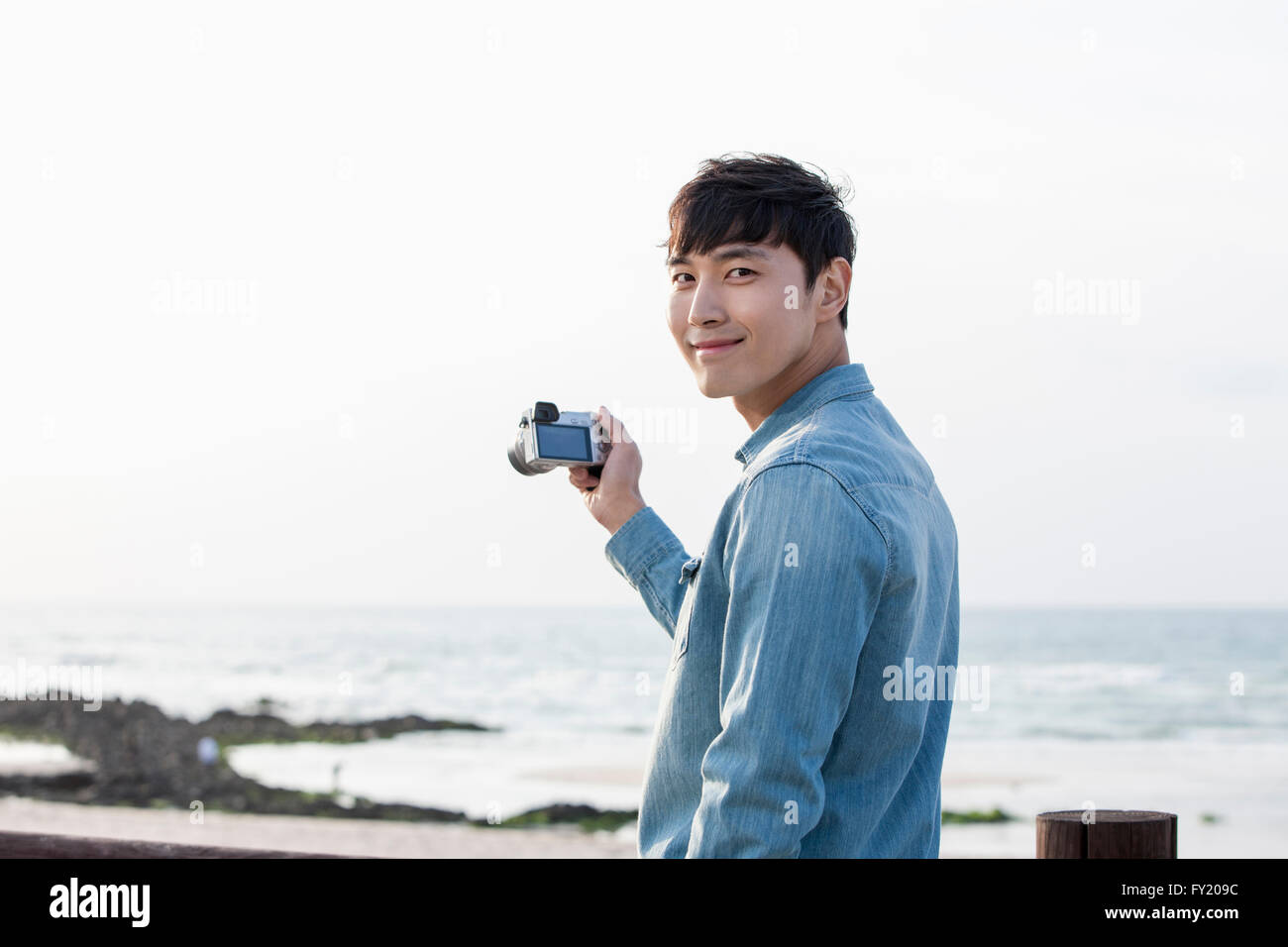 Uomo di scattare una foto con una fotocamera in spiaggia Foto Stock