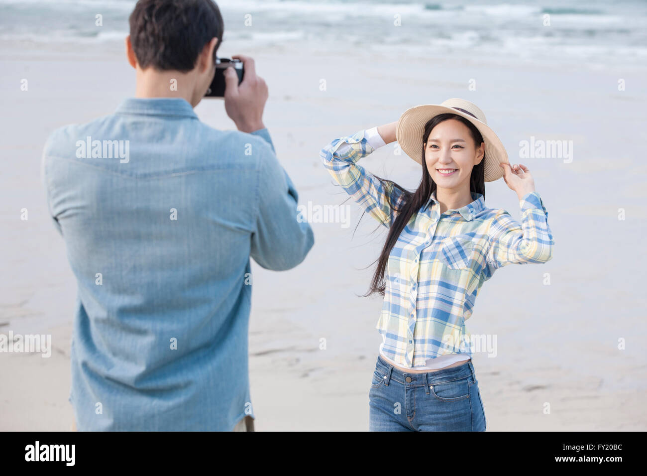 Uomo di scattare una foto della sua fidanzata in spiaggia Foto Stock